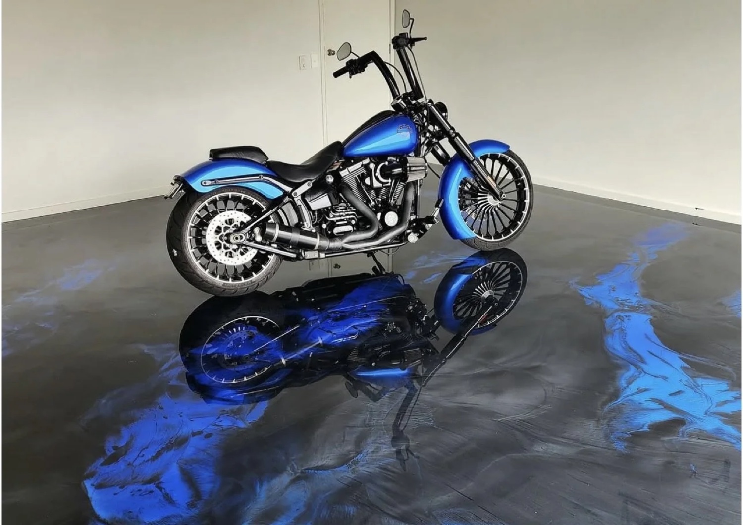 Blue metallic epoxy floor with a custom motorcycle reflected in the finish