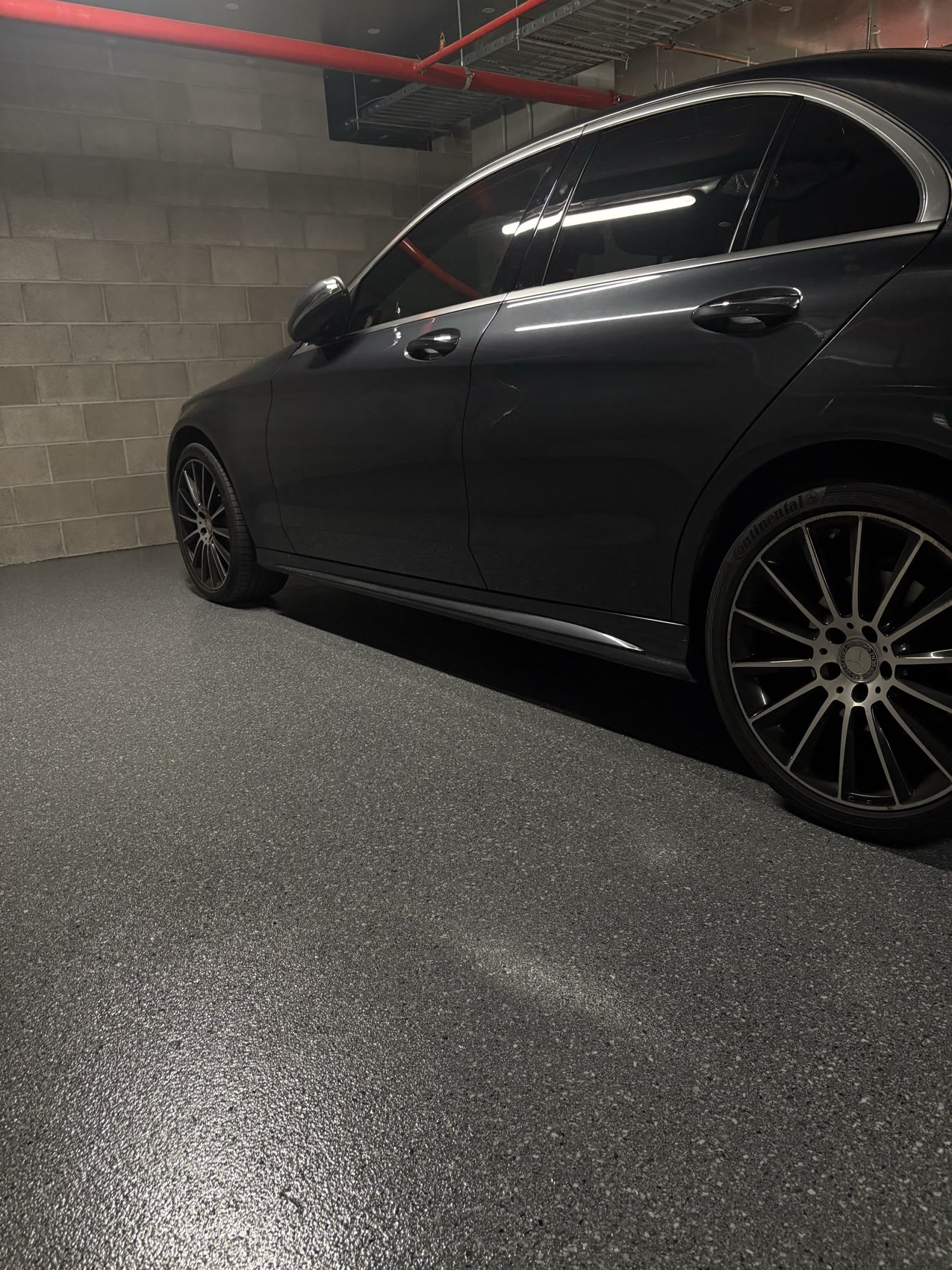 Charcoal epoxy flake floor in a basement garage with a luxury car